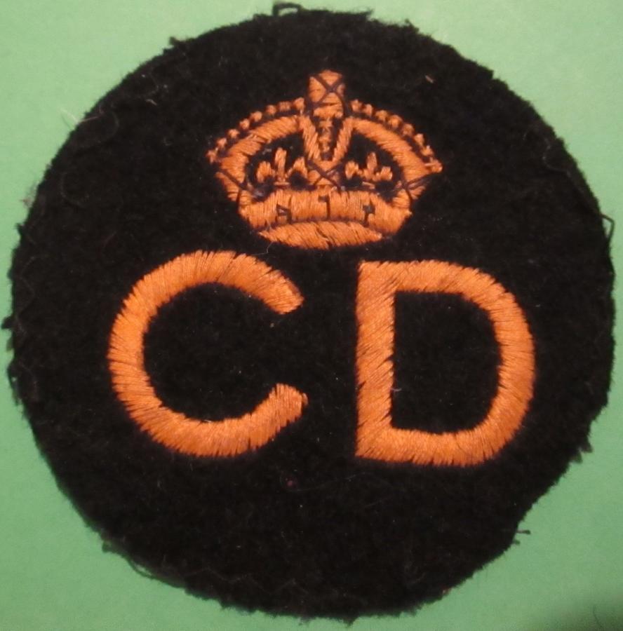 A CIVIL DEFENCE BREAST BADGE CD AND CROWN IN YELLOW
