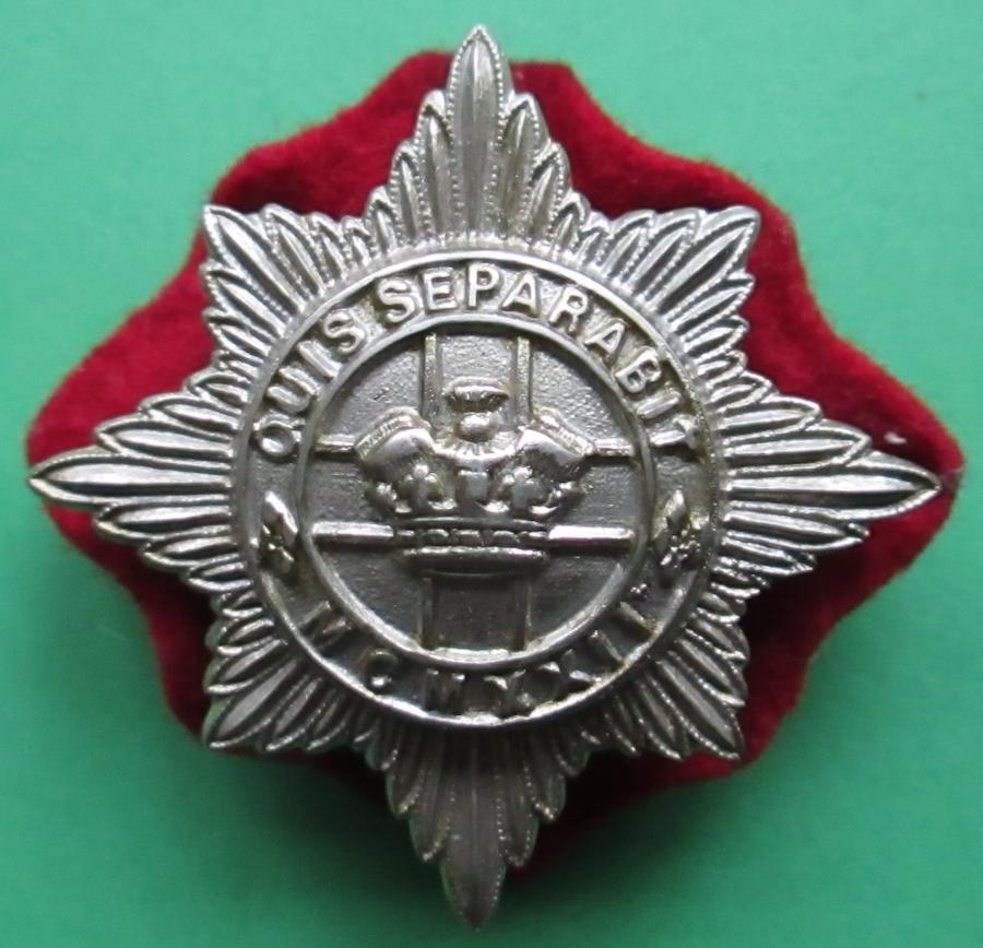 A 4TH / 7TH HUSSARS OTHER RANKS CAP BADGE WITH ITS RED BACKING CLOTH